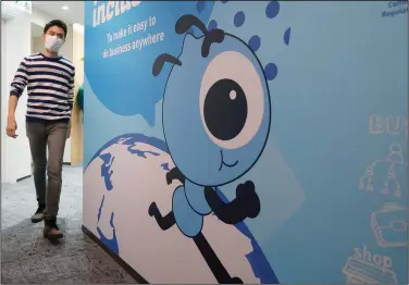  ?? (AP file photo) ?? An employee walks past a graphic of the Ant Group’s mascot at the company’s office in Hong Kong. Ant Group has tangled with Chinese regulators for years as its operations have grown.