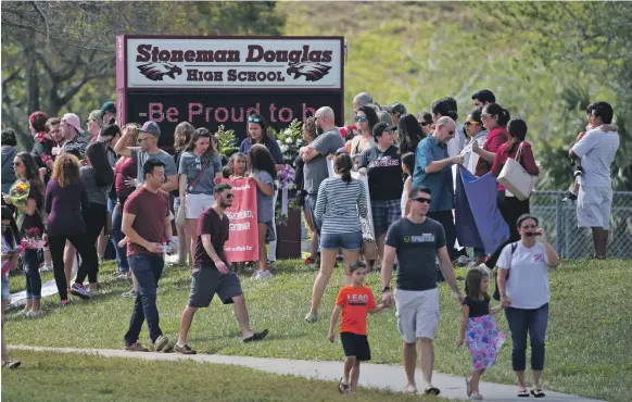  ?? AP ?? Parents and children return to Florida’s Marjory Stoneman Douglas High School for the first time since a mass shooting killed 17 people on February 14