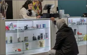  ?? (AP/Ayesha Mir) ?? Alex Silecchia (left), a marijuana “budtender,” also known as a sales associate, serves a customer at Statis Cannabis Company dispensary, late last month in New York.