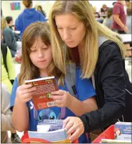  ?? Photo by Mike Eckels ?? Kacie Wood and her mom Allie Wood look for a book.