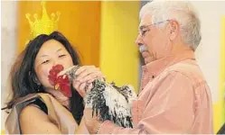  ?? MARIE FARBER ?? Principal Rachel Wilson makes good on her promise to kiss a rooster with help from the bird’s owner, Denis Germain.