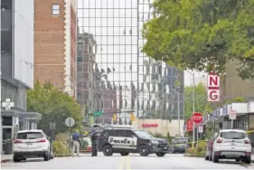  ?? STAFF PHOTO BY C.B. SCHMELTER ?? Police stand near a crime scene on Chestnut Street last October. In Chattanoog­a, 15 of last year’s 34 homicides remain unsolved, a situation complicate­d by the pandemic.