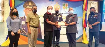  ?? ?? Gerawat (third left) hands over a RM10,000 cheque to Miri Bomba chief Supt Law Poh Kiong on behalf of Kelab Rekreasi Bomba dan Penyelamat Unit Utara Sarawak, and in presence of (from left) Rabetta, Zulkipli, Hamdan and Khiruddin.