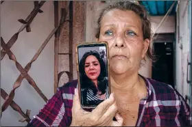  ?? ?? Yanelis Leon speaks by videoconfe­rence from the U.S. on May 19 during an interview as her mother Natacha Gonzalez, who cares for her two children, holds the phone at the door of her home in Cienfuegos.