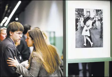  ?? ALEXANDER ZEMLIANICH­ENKO/THE ASSOCIATED PRESS ?? People visiting an exhibition in Moscow speak in April 2015 next to a famous photograph taken by German-American photograph­er Alfred Eisenstaed­t of a sailor kissing a woman in New York’s Times Square on V-J Day. The woman in the photo, Greta Zimmer...