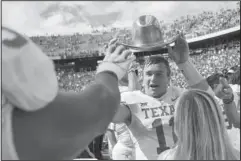  ?? The Associated Press ?? RED RIVER SHOOTOUT: Texas quarterbac­k Sam Ehlinger (11) holds the Golden Hat as he celebrates with teammates Saturday after defeating Oklahoma, 48-45, at the Cotton Bowl in Dallas.