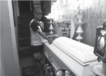  ?? AGENCE
FRANCE PRESSE ?? Saldy Delos Santos, father of the 17 year-old student Kian Loyd stands next to the coffin of his son, allegedly killed by a police anti-drug raid, during a wake at his home in Manila.