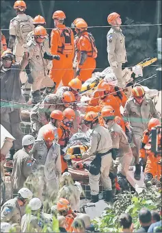  ??  ?? A man is carried on a stretcher as rescue workers are seen at the site of a collapsed building in Muzema community, Rio de Janeiro, Brazil. — Reuters photo