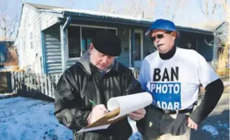  ??  ?? Harley Adams, left, obliges Paul Houston, who is re-collecting signatures to ban red-light cameras and photo radar vans in Sheridan. Photos by Kathryn Scott Osler, The Denver Post