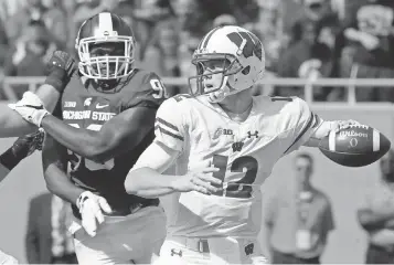  ?? MARK HOFFMAN, MILWAUKEE JOURNAL SENTINEL, VIA USA TODAY SPORTS ?? Wisconsin quarterbac­k Alex Hornibrook ( 12) prepares to fire a pass during the third quarter against Michigan State. The Badgers rolled to a 30- 6 victory.