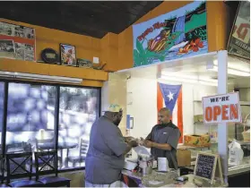  ?? Carlos Avila Gonzalez / The Chronicle ?? Eric Rivera helps Champ Green at Oakland’s Borinquen Soul, which has launched a GoFundMe campaign to assist with relief efforts in Puerto Rico.