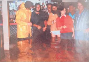 ??  ?? A photo from April 1981 of the Waikino Hotel patrons drinking as the floodwater­s subside. Malou and David Honore can be seen on the right.