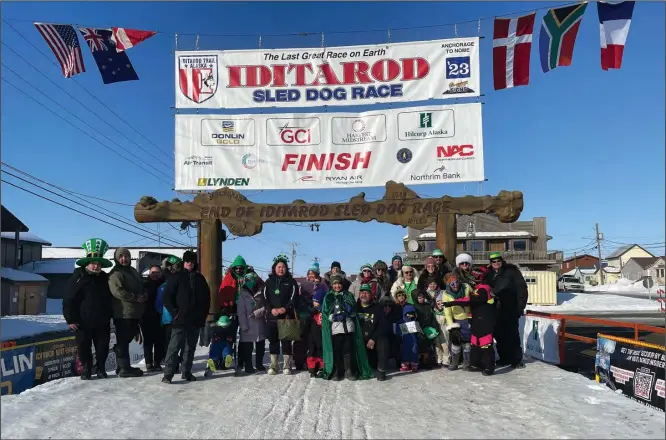  ?? Photo by Lizzy Hahn ?? ST. PATRICK’S DAY IN NOME— As is tradition, Nomeites gathered for a procession down Front Street that ends with a group photo under the burled arch.