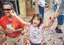  ?? Photos by Billy Calzada / San Antonio Express-News ?? Bella Cathey reaches for rose petals falling from the sky during the procession celebratin­g the Feast of Corpus Christi after Mass at San Fernando Cathedral.