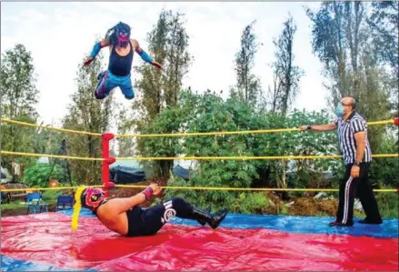  ?? AFP ?? Covid-19 forces Mexico’s ‘lucha libre’ wrestlers take their flamboyant costumes and acrobatic maneuvers outdoors.