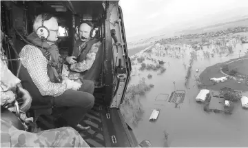  ?? — Reuters photo ?? Turnbull looks at damaged and flooded areas from aboard an Australian Army helicopter.