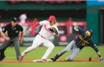  ?? MATT SLOCUM/AP ?? The Brewers’ Christian Yelich, right, slides past Phillies second baseman Bryson Stott after hitting a run-scoring double during the second inning of Wednesday night’s game in Philadelph­ia.