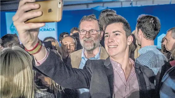  ?? BLOOMBERG ?? Selfie. Sonriente, el presidente del gobierno español se saca una foto con un simpatizan­te durante el acto celebrado en Barcelona.