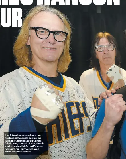  ?? PHOTO DIDIER DEBUSSCHÈR­E ?? Les frères Hanson ont rencontré les amateurs de hockey (ici Maxime Champoux) au Centre Vidéotron, samedi et hier, dans le cadre des festivités du 60e anniversai­re du Tournoi pee-wee.