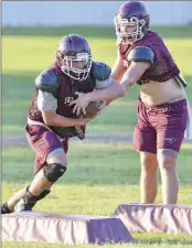  ??  ?? Junior Tyler Givens hands off the ball to sophomore Luke Underwood during summertime drills.