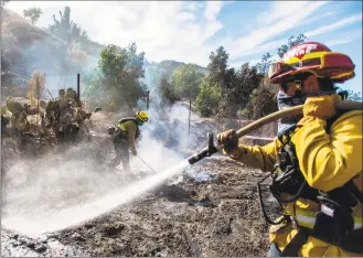  ?? Apu Gomes / AFP via Getty Images ?? Firefighte­rs from Santa Fe Springs battle to control hotspots of the Maria Fire, in Santa Paula, Calif., on Saturday.