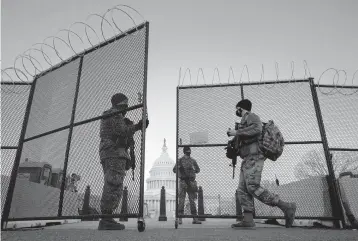  ??  ?? National Guard soldiers open a gate of the perimeter fence around the U.S. Capitol this month in Washington. Security fencing is