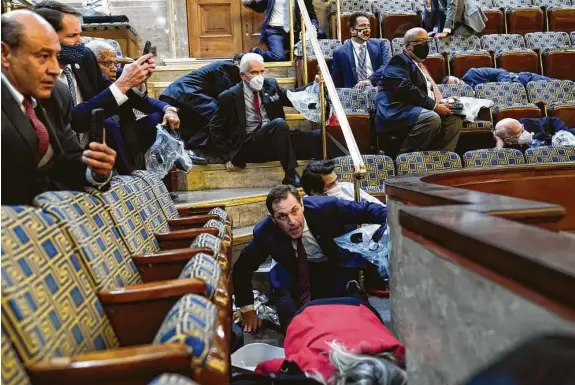  ?? Andrew Harnik / Associated Press ?? People shelter in the House gallery as protesters try to break into the House Chamber. The U.S. Capitol went into lockdown as a mob breached the building.