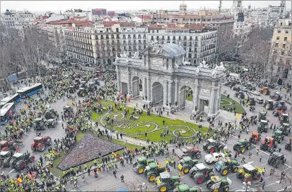  ?? EL PAÍS ?? Madrid. Una fila de tractores aparecen en fila a su paso por la Puerta de Alcalá de esta capital europea, ayer.
