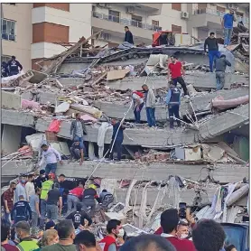  ?? (AP/Ismail Gokmen) ?? Rescue workers and others try to save people trapped in the debris of a collapsed building Friday in Izmir, Turkey, after a strong earthquake struck in the Aegean Sea. At least 19 people were killed and more than 700 injured in building collapses and flooding from a small tsunami, officials said. The quake left at least two people dead on the Greek island of Samos.