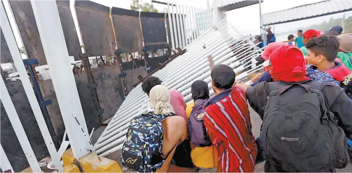  ??  ?? Los viajeros atravesaro­n el puente Suchiate y se toparon con la reja metálica de acceso a México, donde ya estaban desplegado­s los efectivos de la PF.