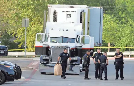  ?? ASSOCIATED PRESS ?? San Antonio police officers investigat­e the scene Sunday where eight people were found dead in a tractor-trailer loaded with at least 30 others outside a Walmart in stifling heat in what police are calling a horrific human traffickin­g case. A ninth...