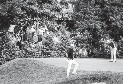  ?? Hilary Swift, © The New York Times Co. ?? Fans on a makeshift stand outside the grounds watch Tiger Woods and Justin Thomas, right, in action on Day 1 of the U. S. Open at Winged Foot Golf Club in Mamaroneck, N. Y., on Thursday.