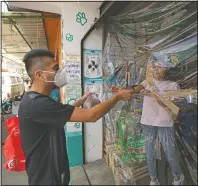  ??  ?? Salas buys food for his pets at a neighborho­od shop with its entrance covered in plastic to curb the spread of the new coronaviru­s.