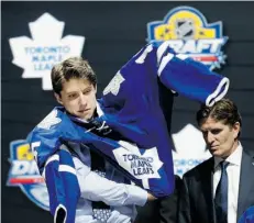  ?? Alan Diaz/The Associated Press ?? Mitch Marner puts on a Toronto Maple Leafs sweater after being chosen fourth overall in the NHL draft on Friday.