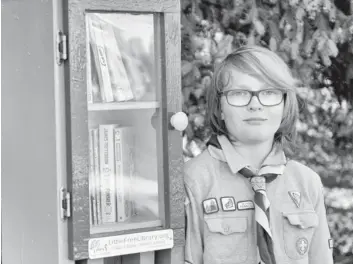  ?? [ALI WILSON / THE OBSERVER] ?? Hayden George with the first registered Little Free Library in Elmira, which he installed on Barnswallo­w Drive.