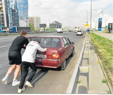  ?? OLEG PETRASYUK / EFE ?? Dos personas empujan un coche hasta la cola de una gasolinera en Kiev.