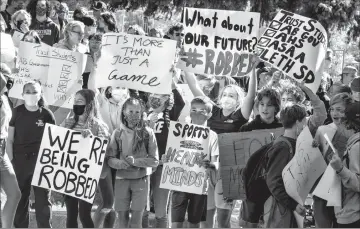  ?? Herald photo by Ian Martens ?? A crowd of students holds signs as they stage a protest Thursday in front of the Lethbridge School Division offices demanding a return of sports and extracurri­cular activities. @IMartensHe­rald