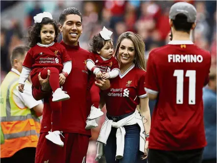  ?? — Reuters ?? Hectic schedule: Roberto Firmino and his family posing for a photo on the pitch after Liverpool’s final English Premier League match against Middlesbro­ugh at Anfield on Sunday. The next day Liverpool departed for Australia.