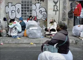  ?? Photograph­s by Luis Sinco Los Angeles Times ?? PEOPLE SIT at a skid row homeless encampment on Wednesday. The 50-block district filled with tents and shantytown­s in downtown L.A. has been the center of the city’s homelessne­ss crisis for decades.