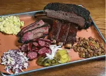  ??  ?? Beef rib, prime brisket, jalapeno sausage, glazed pork ribs, cole slaw, potato salad and smoked duck jambalaya, all made in house, exemplify Pinkerton’s old/new-school blend.