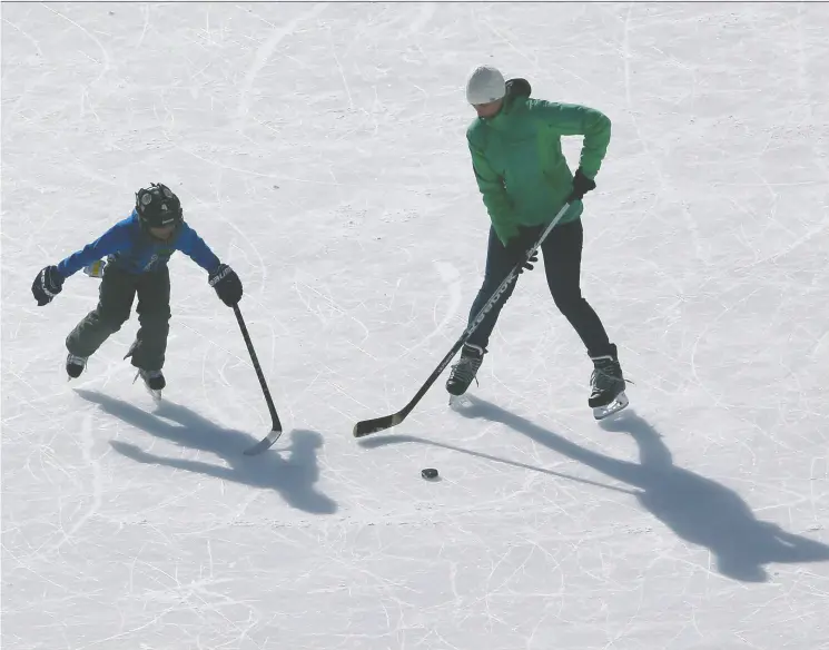  ?? Tom Szczerbows­ki
/ Getty
Images ?? Moms, like this one seen giving her son tips on puck-handling skills on a frozen lake, serve as role models for many of the game’s greatest players.