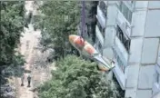  ?? REUTERS ?? People watch as a defused 500kg bomb that did not detonate when it landed on an apartment building in March, is lowered from the roof in the Saltivka neighbourh­ood, in Kharkiv, Ukraine.