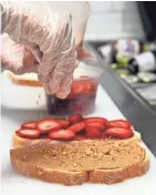  ?? ANGELA PETERSON/MILWAUKEE JOURNAL SENTINEL ?? Selina Domenech makes the Strawberry Lovers sandwich at the Peanut Butter &amp; Jelly Deli.