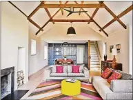  ?? ?? This living room (one of two) is an example of mixing old and new, with country-style built-ins and wooden ceiling beams playing with vibrant fabrics.