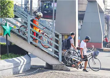  ?? PHOTOGRAPH­S BY DIANNE BACELONIA FOR THE DAILY TRIBUNE ?? BIKERS carry their bikes while using the overpass along a street in Marikina City on Friday, making sure that they will not be involved in accidents while crossing the road.