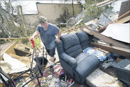  ?? GERALD HERBERT — THE ASSOCIATED PRESS ?? Bradley Beard walks with a shovel through his daughter’s destroyed trailer home, after searching in vain for the water shutoff valve for the property in the aftermath of Hurricane Laura, Saturday, Aug. 29, 2020 in Hackberry, La.
