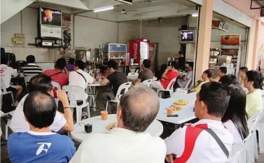  ??  ?? Spellbound by speakers: People in a coffeeshop watching the debate between Dr Chua and Lim in Taman Bukit Perdana on
Saturday.