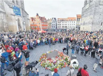  ?? FOTO: DPA ?? Zahlreiche Menschen stehen in Halle auf dem Marktplatz und bringen Blumen und Kerzen, um ein Zeichen gegen Gewalt zu setzen.