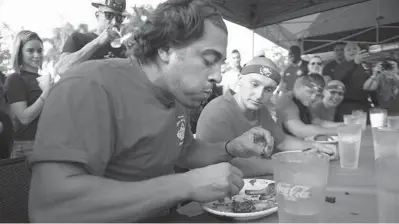  ?? MICHAEL LAUGHLIN/SUN SENTINEL ?? Firefighte­r Robert Gendreau competes in the Guns and Hoses Rib Eating Challenge between the city of Miramar’s police officers and firefighte­rs at Texas Roadhouse recently. The firefighte­rs won the challenge.