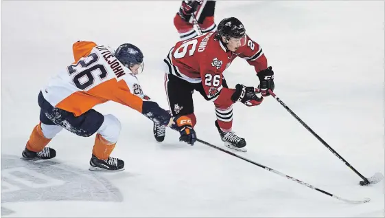  ?? JULIE JOCSAK ST. CATHARINES STANDARD ?? Philip Tomasino of the Niagara IceDogs tries to keep the puck ahead of Ryan Littlejohn of the Flint Firebirds in this OHL file photo.